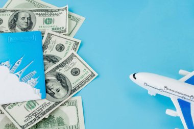 Pasaportunda yolcu uçağı modeli ve mavi arka planda dolar var. Seyahat kavramı, kopyalama alanı