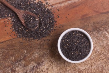 Ahşap bir masa üzerinde bir kasede siyah susam