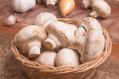 Ahşap bir masa üzerinde bir sepet içinde taze champignon mantar