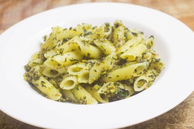 Ahşap bir masa üzerinde izole pesto soslu penne makarna