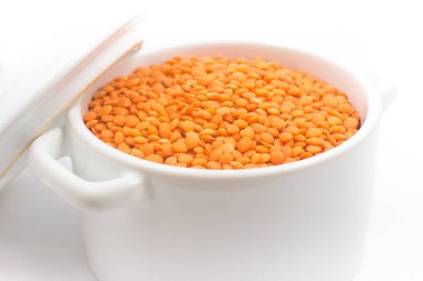 Küçük bir tavada beyaz bir arka plan üzerinde kırmızı mercimek