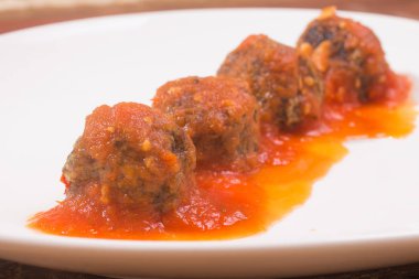 Ahşap bir masa üzerinde köfte ve domates soslu