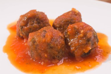 Ahşap bir masa üzerinde köfte ve domates soslu