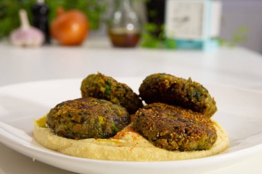 Beyaz bir masanın üzerinde nohut humusuyla Mercimek Kibbeh