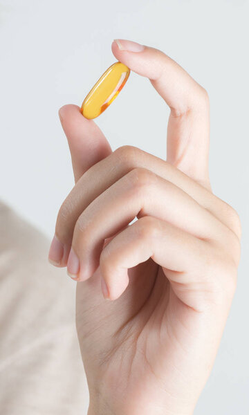 Closeup woman hand showing Fish oil capsules.