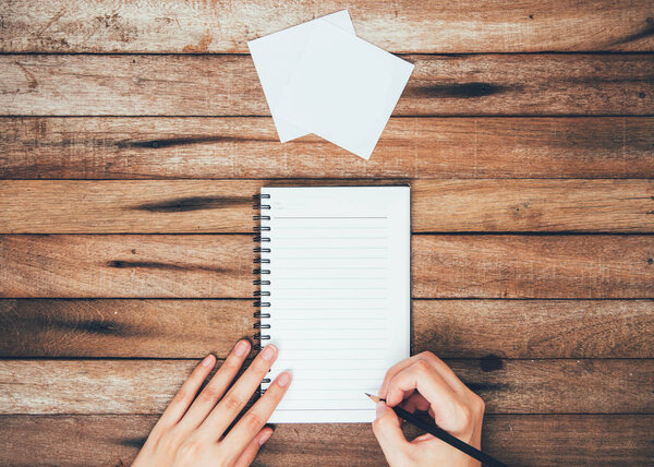 woman hands writting down on the book Top View on wooden table Top View with Copy Space, on vintage background.