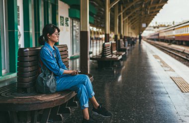 Bekleyen trenin Tren İstasyonu-seyahat ve ulaşım kavramı platformunda siting Asyalı kadın gezgin