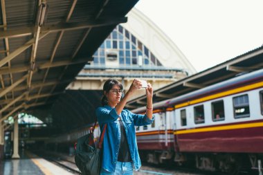 Asyalı kadın gezgin kullanılan akıllı telefon almak fotoğraf Tren Tren İstasyonu - platform zamanında bekle ve onay süre seyahat ve ulaşım kavramı