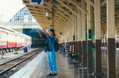 Asyalı kadın gezgin kullanılan akıllı telefon almak fotoğraf bekleyin ve