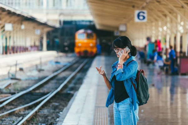 Asyalı kadın kullanılan gezgin akıllı telefon bekleyin ve onay zamanlama Tren İstasyonu - platform üzerinde tren iken parmak sayma ile seyahat ve ulaşım kavramı