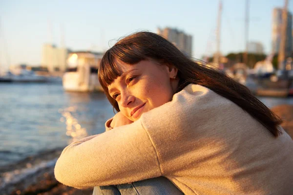 nice young woman sitting on the beach at sunset