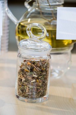 Cam çaydanlıkta demlenmiş bitki çayı ve şişede çay bitkisi.