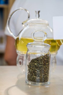 Cam çaydanlıkta demlenmiş bitki çayı ve şişede çay bitkisi.
