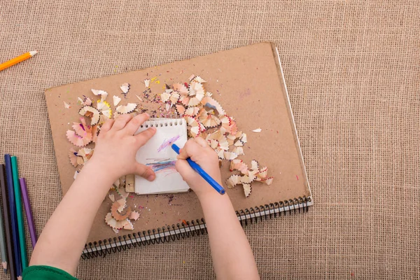 Elinde kalem çöpü olan sarmal defterlerin üzerinde renkli bir kalem tutuyordu.