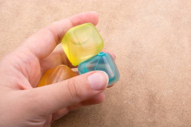 Kahverengi arka planda sahte renkli buz küpleri tutuyor.