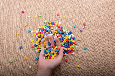 Elindeki ve yerdeki renkli çakıl taşları