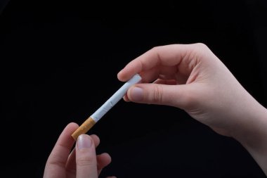 Siyah arka planda bir el sigara tutuyor.
