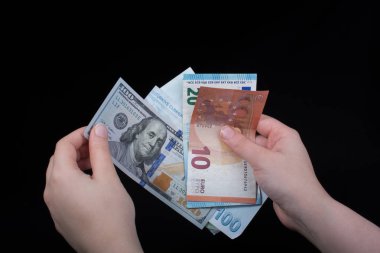 El ele tutuşan Amerikan doları banknotları siyah arka planda izole edilmiş.