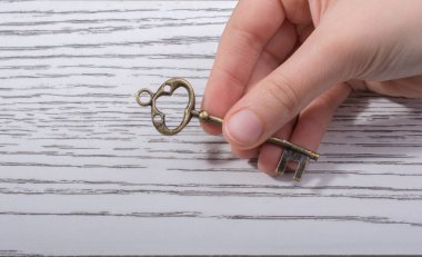 Ahşap doku üzerinde bir retro tasarımlı dekoratif anahtar tutan el