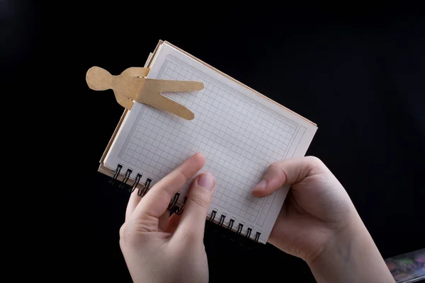 Man shape cut out of paper in notebbok in hand