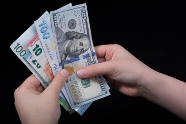 El ele tutuşan Amerikan doları banknotları siyah arka planda izole edilmiş.