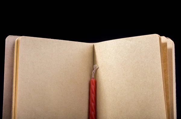 黑色背景上的蜡烛和打开的棕色彩色笔记本 — 图库照片