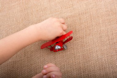 Kırmızı oyuncak uçağa keten bir tuval üzerinde tutan el