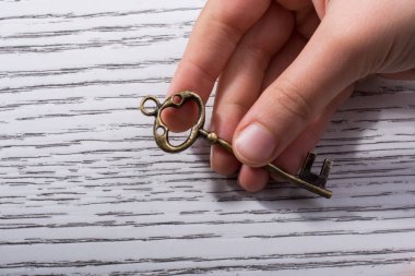 Ahşap doku üzerinde bir retro tasarımlı dekoratif anahtar tutan el