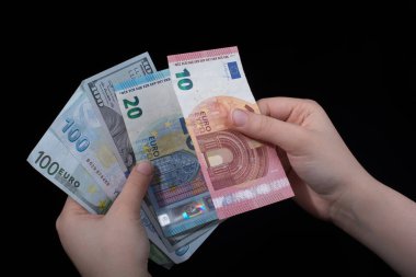 El ele tutuşan Amerikan doları banknotları siyah arka planda izole edilmiş.