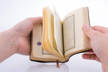 Beyaz arka planda Kuran 'ı el ele tutuşarak.