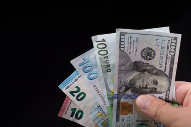 El ele tutuşan Amerikan doları banknotları siyah arka planda izole edilmiş.