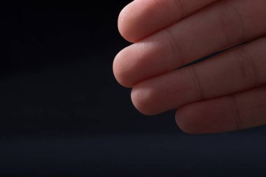 Bir çocuğun dört parmağı kısmen siyah arkaplanda görülüyor