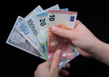 El ele tutuşan Amerikan doları banknotları siyah arka planda izole edilmiş.