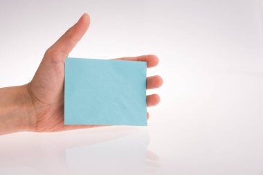 Beyaz bir arka plan üzerine açık mavi renk dikdörtgen kağıt tutan el