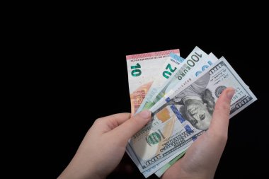 El ele tutuşan Amerikan doları banknotları siyah arka planda izole edilmiş.