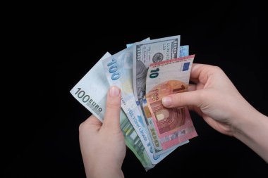 El ele tutuşan Amerikan doları banknotları siyah arka planda izole edilmiş.