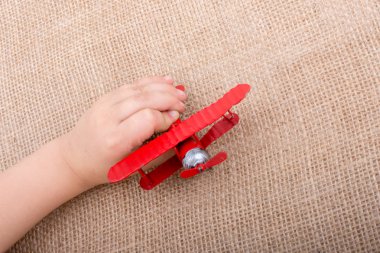 Kırmızı oyuncak uçağa keten bir tuval üzerinde tutan el