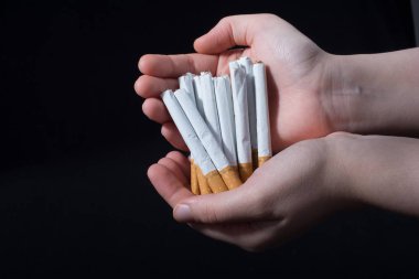 El, siyah arka planda bir paket sigara dağıtıyor.