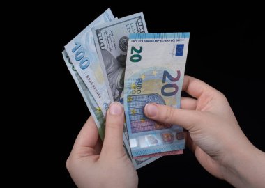 El ele tutuşan Amerikan doları banknotları siyah arka planda izole edilmiş.