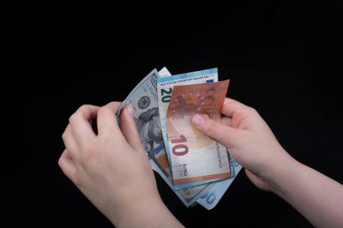 El ele tutuşan Amerikan doları banknotları siyah arka planda izole edilmiş.