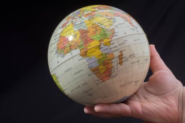 Üzerinde harita olan bir küreyi tutan el.