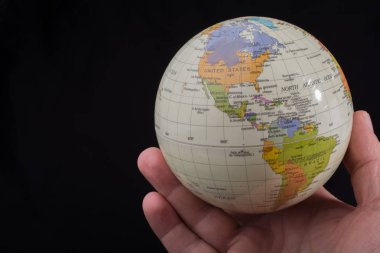 Üzerinde harita olan bir küreyi tutan el.