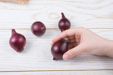 Tüm kırmızı soğan soğanları kahverengi ve ahşap arka planda