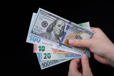 El ele tutuşan Amerikan doları banknotları siyah arka planda izole edilmiş.