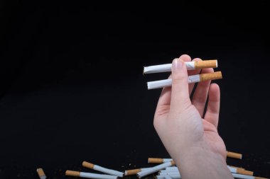 Siyah arka planda sigara tutan bir el var.