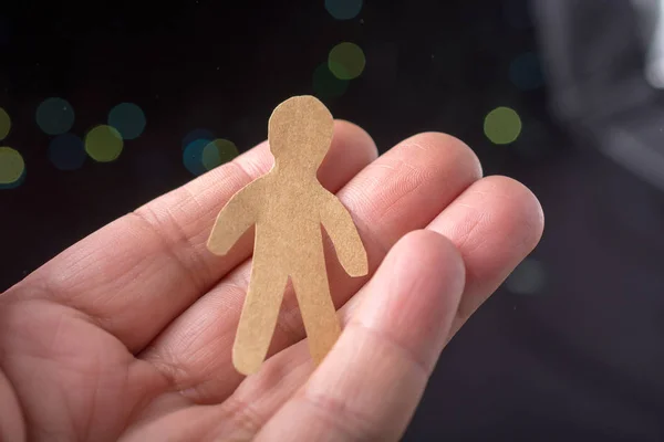 Paper man shape in hand on bokeh light background