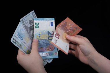 El ele tutuşan Amerikan doları banknotları siyah arka planda izole edilmiş.