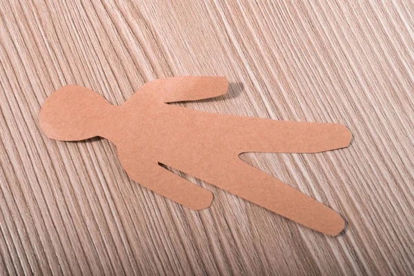 Man shape cut out of paper on wooden texture