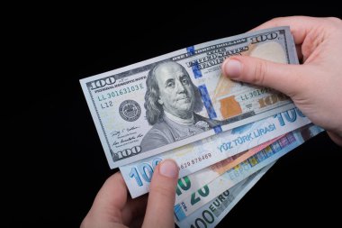 El ele tutuşan Amerikan doları banknotları siyah arka planda izole edilmiş.