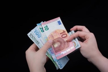 El ele tutuşan Amerikan doları banknotları siyah arka planda izole edilmiş.